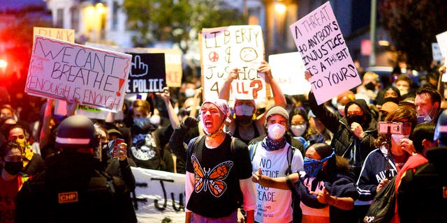 In this May 29, 2020, photo, demonstrators face off against police officers in Oakland, Calif. while protesting the Monday death of George Floyd, a handcuffed black man in police custody in Minneapolis. (AP Photo/Noah Berger)