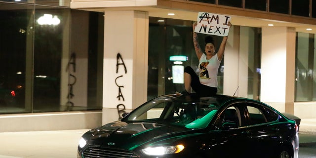 A protester rides on the top of a car during a protest over the deaths of George Floyd and Breonna Taylor, Friday, May 29, 2020, in Louisville, Ky. Breonna Taylor, a black woman, was fatally shot by police in her home in March. (AP Photo/Darron Cummings)