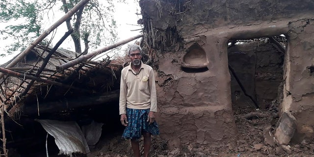 This photo provided by the Indian Red Cross Society shows a villager standing outside his damaged house after Cyclone Amphan, the equivalent of a category 3 hurricane, hit the area in Bhadrak district of Orissa state, May 21. (Indian Red Cross Society via AP)