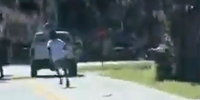This image from video posted on Twitter Tuesday, May 5, 2020, purports to show Ahmaud Arbery running on a street in a neighborhood outside Brunswick, Ga., on Feb. 23, 2020, as a pickup truck is stopped in front of him. (Twitter via AP)