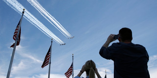 People view the U.S. Navy Blue Angels and U.S. Air Force Thunderbirds from the Washington Monument as they fly over the National Mall in Washington, Saturday, May 2, 2020. The flyover was in salute to first responders in the fight against the coronavirus pandemic. (AP Photo/Patrick Semansky)