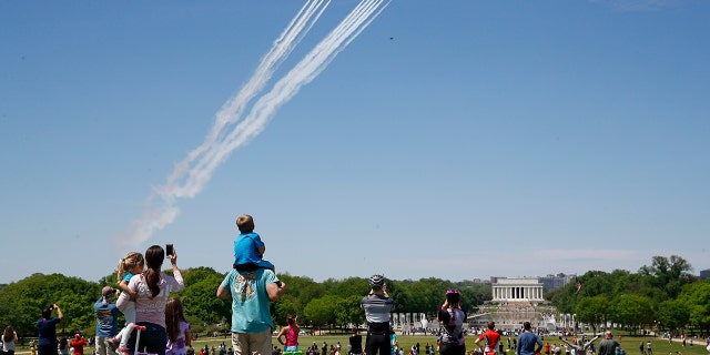 People view the U.S. Navy Blue Angels and U.S. Air Force Thunderbirds as they fly over the National Mall in Washington, Saturday, May 2, 2020. The flyover was in salute to first responders in the fight against the coronavirus pandemic. (AP Photo/Patrick Semansky)
