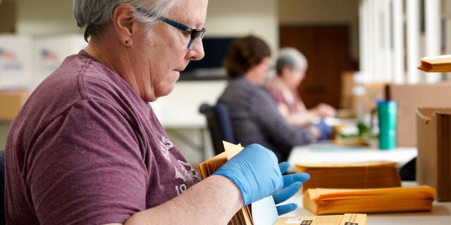 Pam Fleming and fellow workers stuff ballots and instructions into mail-in envelopes at the Lancaster County Election Committee offices in Lincoln, Neb., April 14, 2020. (Associated Press)