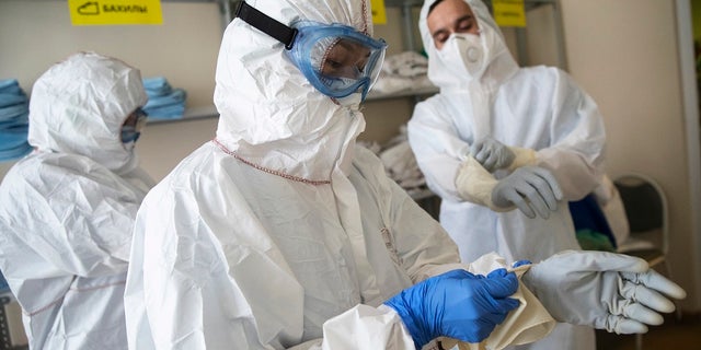 Medical workers put on protective gear in order to assist coronavirus patients at the intensive care unit of Vinogradov City Clinical Hospital in Moscow. Three Russian health care workers have fallen out of hospital windows in recent weeks after complaints about a lack of equipment and becoming infected. (AP Photo/Pavel Golovkin)