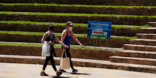 Woman wearing face masks pas the Arneson Theater along the River Walk in San Antonio, Thursday, April 30, 2020. Texas Gov. Greg Abbott is allowing stay-at-home orders to expire Thursday, as he looks to open the state, but San Antonio has extended stay-at-home orders through May 19 and maintains the requirement of wearing a face mask or other face covering when near others.