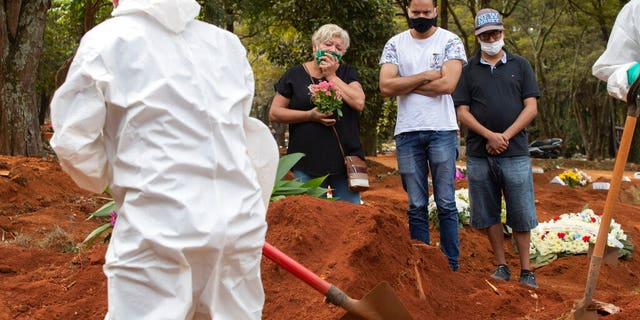 Relatives attend the burial of the remains of a person suspected to have died of COVID-19 disease, at the Vila Formosa cemetery in Sao Paulo, Brazil, Thursday, April 30, 2020.