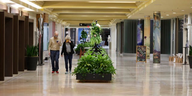 A couple takes a walk at Eton Chagrin Boulevard, an indoor mall filled with retail shops and speciality stores, now closed due to the coronavirus epidemic, Thursday, April 30, 2020, in Woodmere Village, Ohio.
