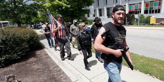 People with weapons march in Raleigh, N.C., Friday, May 1, 2020. About a dozen demonstrators marched Friday afternoon around the area of the Old Capitol, Legislative Building, and Executive Mansion. Several had visible firearms. A Facebook post calling for a rally on Friday morning had said it was to promote constitutional free speech and gun rights. (AP Photo/Gerry Broome)