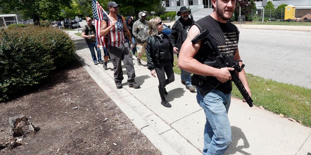 People with weapons march in Raleigh, N.C., Friday, May 1, 2020. About a dozen demonstrators marched Friday afternoon around the area of the Old Capitol, Legislative Building, and Executive Mansion. Several had visible firearms. A Facebook post calling for a rally on Friday morning had said it was to promote constitutional free speech and gun rights. (AP Photo/Gerry Broome)