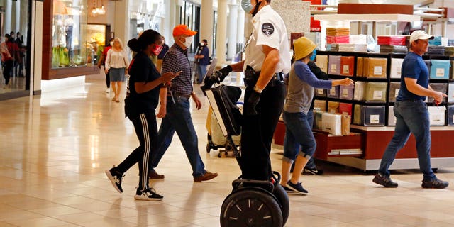 A security guard wearing a mask and riding a Segway patrols inside Penn Square Mall as the mall reopens Friday, May 1, 2020, in Oklahoma City.