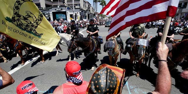 Law enforcement personnel on horseback keep protesters on the sidewalk during a demonstration at the pier Friday, May 1, 2020, in Huntington Beach, Calif., during the coronavirus outbreak. (Associated Press)