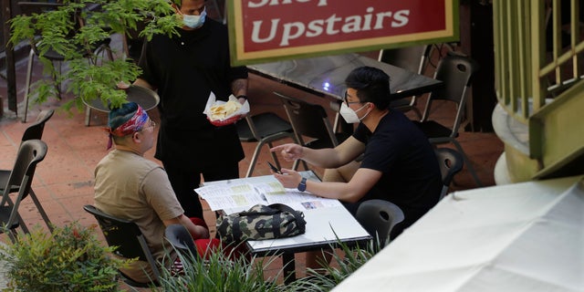 A waiter serves a group dining at a restaurant that reopened at the River Walk in San Antonio, Friday, May 1, 2020. (Associated Press)