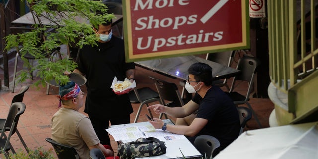 A waiter serves a group dinning at a restaurant that reopen at the River Walk in San Antonio, Friday, May 1, 2020. Texas' stay-at-home orders due to the COVID-19 pandemic have expired and Texas Gov. Greg Abbott has eased restrictions on many businesses that have now opened. (AP Photo/Eric Gay)