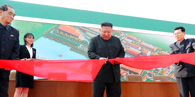 In this Friday, May 1, 2020, photo provided by the North Korean government, North Korean leader Kim Jong Un, center, cuts a tape, watched by his sister Kim Yo Jong, during his visit to a fertilizer factory in Sunchon, South Pyongan province, near Pyongyang, North Korea. 