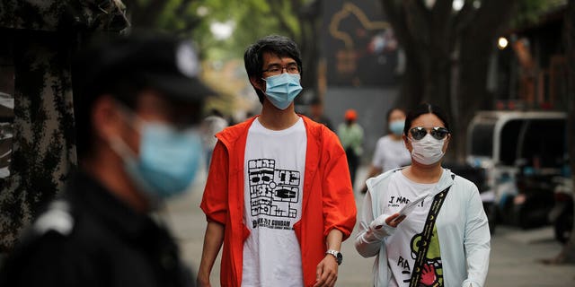 People wearing protective face masks to help curb the spread of the coronavirus, walking through Beijing's popular tourist spot of Nanluonguxiang on Sunday.