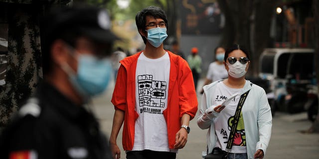 People wearing protective face masks to help curb the spread of the coronavirus, walking through Beijing's popular tourist spot of Nanluonguxiang on Sunday.