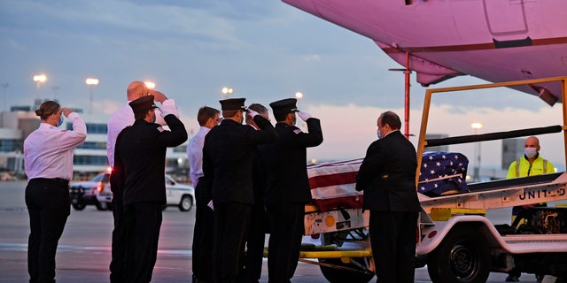 Ambulnz paramedics and Aurora firefighters salute as the casket carrying the body of paramedic Paul Cary is removed from a plane at Denver International Airport on Sunday, May 3, 2020, in Denver. Cary died from coronavirus after volunteering to help combat the pandemic in New York City. (Helen H. Richardson/The Denver Post via AP, Pool)