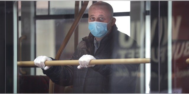 A man wears a mask to protect against the coronavirus as he looks out of the window of a bus in London, Monday, May 4, 2020, as the UK enters a seventh week of lockdown to help stop the spread of coronavirus. The highly contagious COVID-19 coronavirus has impacted on nations around the globe, many imposing self isolation and exercising social distancing when people move from their homes. 