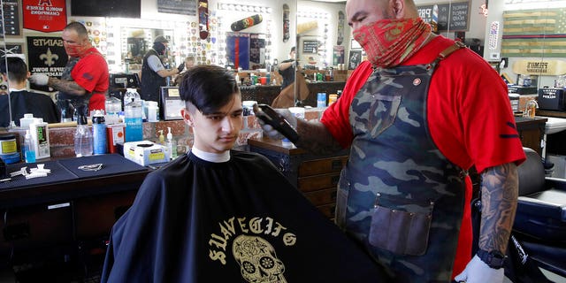 Juan Desmarais, right, the owner of Primo's Barbershop in Vacaville, Calif., on Monday.