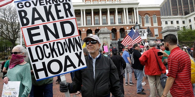 Demonstrators display flags and placards during a protest Monday in front of the Statehouse, in Boston. Protesters gathered in front of the Statehouse Monday to protest restrictions on movement and businesses prompted by the COVID-19 outbreak. (AP Photo/Steven Senne)