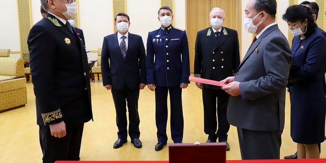 Russian Ambassador to Democratic People's Republic of Korea Alexander Matsegora, left, and Democratic People's Republic of Korea Foreign Minister Ri Son-gwon, foreground right, both wearing face masks to protect against coronavirus, attend a ceremony of awarding North Korean leader Kim Jong-un with Russia's 75th anniversary Victory medal for his major contribution in commemorating Soviet soldiers, who died in 1945 during Korea's liberation, at the Mansudae Palace of Congress in Pyongyang, North Korea. (Russian Embassy in the DPRK/Russian Foreign Ministry Press Service via AP)