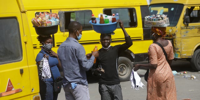People wearing face masks sells snacks and water to passengers at Obalende bus station in Lagos Nigeria, Tuesday May 5, 2020. Though Nigeria begun a phased easing of its strict lockdown measures on Monday, its confirmed cases of coronavirus continue to increase. (AP Photo/Sunday Alamba)
