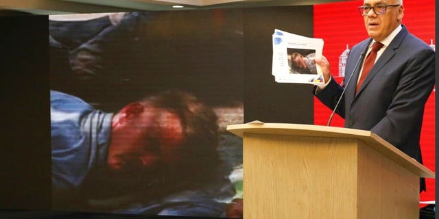 In this photo released by the Venezuelan Communications Ministry press office, Communications Minister Jorge Rodriguez shows a photograph of a man he identifies as former U.S. special forces soldier Luke Denman and taken in Venezuela during his arrest, in Caracas, Venezuela, Tuesday, May 5, 2020. Venezuelan authorities say they arrested Denman and one other U.S. citizen among a group of “mercenaries” on Monday, a day after a beach raid purportedly aimed at capturing the leader that Venezuelan authorities say they foiled.