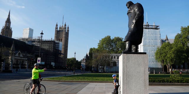 A man takes a photo in front of the statue of Britain's wartime Prime Minister Winston Churchill in an almost empty Parliament Square in London, Friday, May 8, 2020 on the 75th anniversary of the end of World War II in Europe.