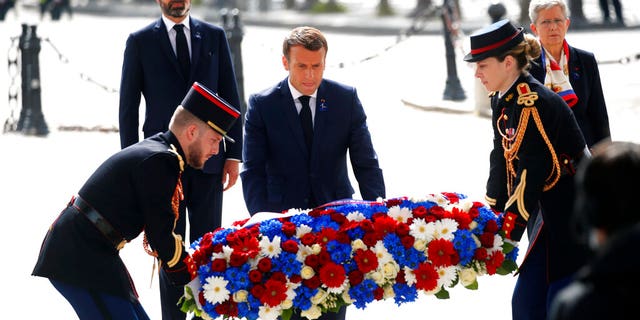 French President Emmanuel Macron lays a wreath of flowers during a ceremony to mark the 75th anniversary of the World War II victory over Nazi Germany, at the Arc de Triomphe in Paris, Friday May 8, 2020. The ceremony was marked by the absence of public and complete silence in the streets of central Paris, as all gatherings are banned under France's confinement measures. At left behind is French Prime Minister Edouard Philippe.