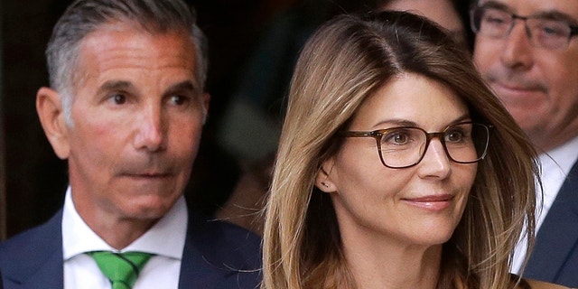 In this April 3, 2019, file photo, actress Lori Loughlin, front, and her husband, clothing designer Mossimo Giannulli, left, depart federal court in Boston after a hearing in a nationwide college admissions bribery scandal. A federal judge on Friday, May 8, 2020, refused to dismiss charges against the couple and other prominent parents accused of cheating in the college admissions process, siding with prosecutors who denied that investigators had fabricated evidence. (AP Photo/Steven Senne