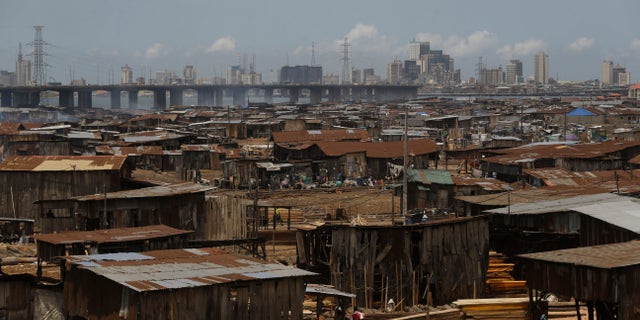 People from a slum work in a sawmill overlooking Lagos downtown in Nigeria, Tuesday May 12, 2020. Though Nigeria began a phased easing of its strict lockdown measures on May 4, its confirmed cases of coronavirus continue to increase. (AP Photo/Sunday Alamba)