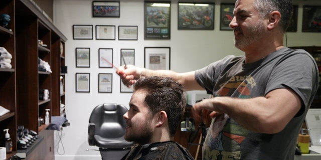 Cathedral Junction Barbers owner Conrad Fitz-Gerald cuts the hair of his son Heathcliff just past midnight in Christchurch, New Zealand. (AP Photo/Mark Baker)