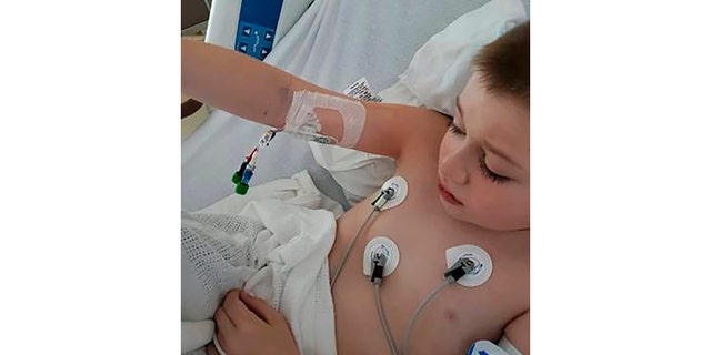 In this 2020 photo provided by Amber Dean 9-year-old Bobby Dean lies in a hospital bed in Rochester, N.Y., after being admitted with severe dehydration, abdominal pain and a racing heart. He tested positive for coronavirus at the hospital and the doctors diagnosed him with a pediatric inflammatory syndrome related to the virus. (Dean Family Photo via AP)