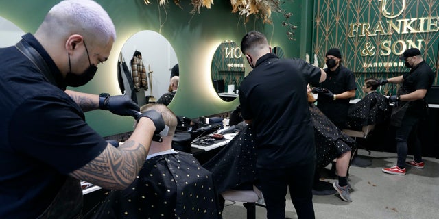 Barbers cut customers' hair in Christchurch, New Zealand, Thursday, May 14, 2020. (AP Photo/Mark Baker)