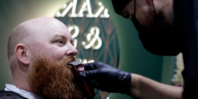 A man has his beard trimmed at a barber in Christchurch, New Zealand, Thursday, May 14, 2020. New Zealand lifted most of its remaining lockdown restrictions from midnight Wednesday (noon Wed GMT) as the country prepares for a new normal. Malls, retail stores and restaurants will reopen and many people will return to their workplaces.