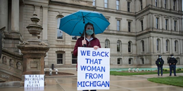 A counter protester holds a sign supporting Michigan Gov. Gretchen Whitmer's stay-at-home order during a rally at the State Capitol in Lansing, Mich., Thursday. (AP Photo/Paul Sancya)