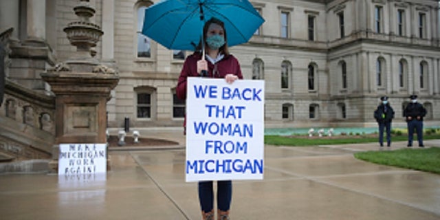 A counter protester holds a sign supporting Michigan Gov. Gretchen Whitmer's stay-at-home order during a rally at the State Capitol in Lansing, Mich., Thursday. (AP Photo/Paul Sancya)