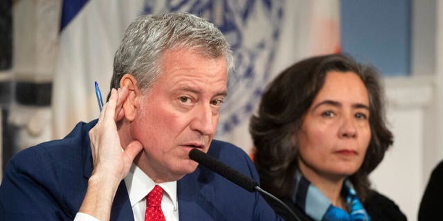 Mayor Bill de Blasio, left, with Dr. Oxiris Barbot, commissioner of the New York City Department of Health and Mental Hygiene, listens to a reporter's question in New York on Feb. 26, 2020. (AP Photo/Mark Lennihan, File)