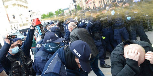 Police firing tear gas toward protesters demanding an end to economic restrictions during the coronavirus pandemic in Warsaw, Poland, on Saturday.