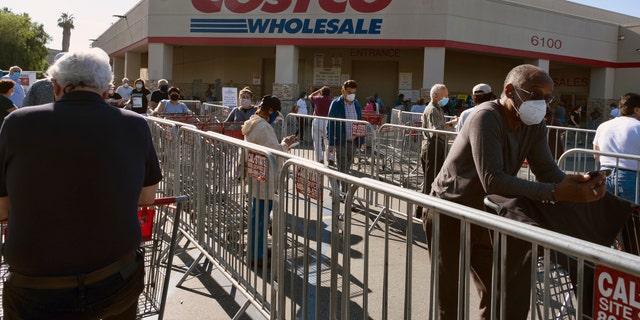 Customers wearing protective masks from the coronavirus and keeping social distancing space line up to enter a Costco Wholesale store in the Van Nuys section of Los Angeles on Saturday. (AP Photo/Richard Vogel)