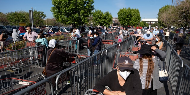Customers wearing protective masks from the coronavirus and keeping social distancing space line up to enter a Costco Wholesale store in the Van Nuys section of Los Angeles, Saturday, May 16, 2020. (AP Photo/Richard Vogel)