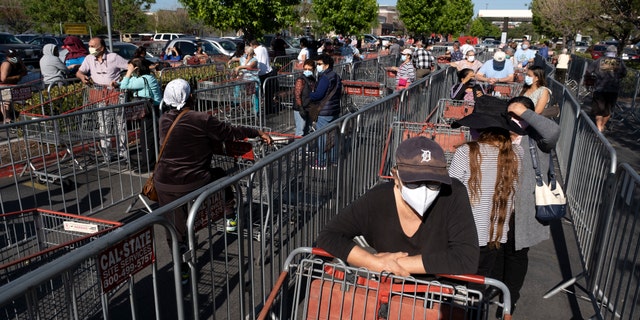 Customers wearing protective masks from the coronavirus and keeping social distancing space line up to enter a Costco Wholesale store in the Van Nuys section of Los Angeles, Saturday, May 16, 2020. (AP Photo/Richard Vogel)