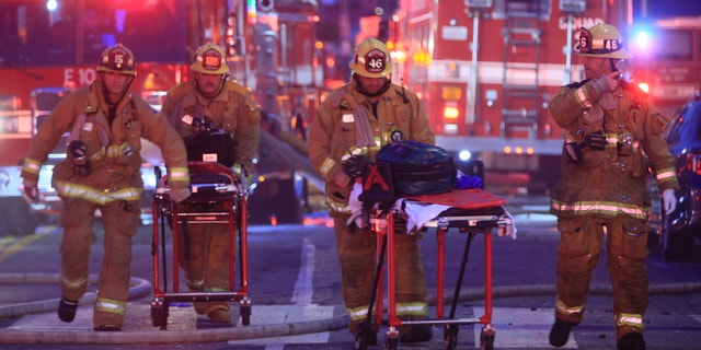 Los Angeles Fire Department firefighters push ambulance cots at the scene of a structure fire that injured multiple firefighters, according to a fire department spokesman, Saturday, May 16, 2020, in Los Angeles. (Associated Press)