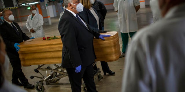 Mortuary service workers on Sunday carrying the coffin of the last COVID-19 victim stored at an underground parking garage that was turned into a morgue, at the Collserola funeral home in Barcelona, Spain. (AP Photo/Emilio Morenatti)