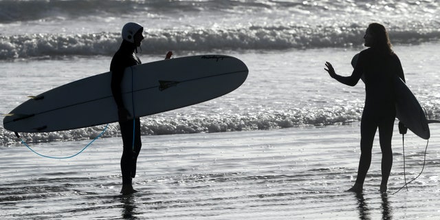 Surfers gesture as the talk before entering the water at Sumner Beach near in Christchurch, New Zealand, May 18. (AP Photo/Mark Baker)