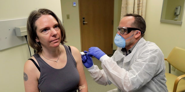 In this March 16, 2020, file photo, a pharmacist gives Jennifer Haller, left, the first shot in the first-stage safety study clinical trial of a potential vaccine for COVID-19 at the Kaiser Permanente Washington Health Research Institute in Seattle. 