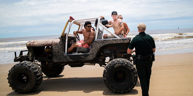 A group of people riding in a Jeep during the Go Topless Jeep Weekend event get stopped by a Galveston County Sheriff's Office deputy at Crystal Beach on Bolivar Peninsula last year. (AP/Houston Chronicle)