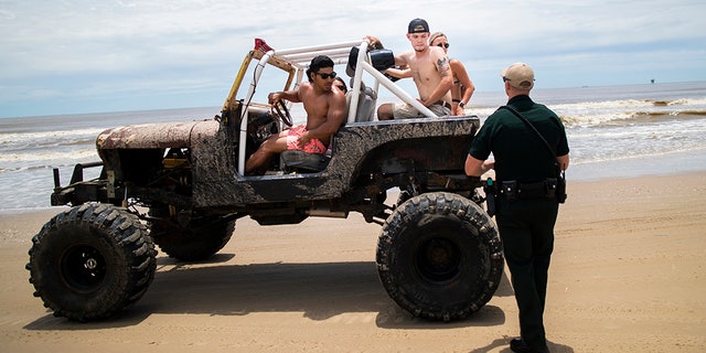 A group of people riding in a Jeep during the Go Topless Jeep Weekend event get stopped by a Galveston County Sheriff's Office deputy at Crystal Beach on Bolivar Peninsula last year. (AP/Houston Chronicle)