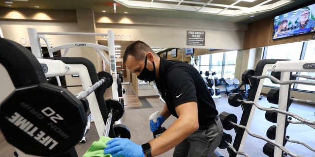 Jason Nichols, responsable des opérations des installations, désinfecte l'équipement du Life Time Biltmore lors de son ouverture après sa fermeture en raison du coronavirus le lundi 18 mai 2020 à Phoenix. 
