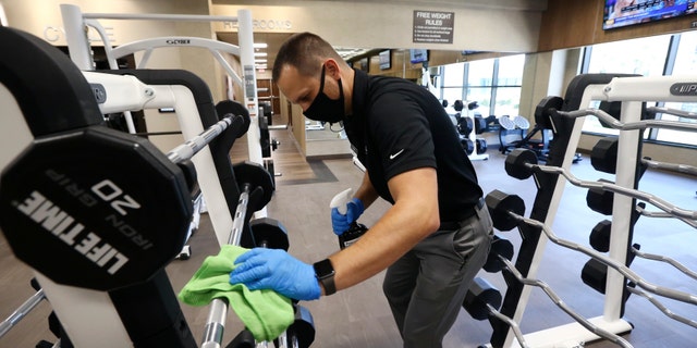 Jason Nichols, facilities operations manager, cleans equipment at Life Time Biltmore as it opens for business after being closed due to the coronavirus Monday, May 18, 2020, in Phoenix.